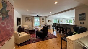 A spacious living area with a sofa, armchairs, a coffee table, and a dining area with bar stools.