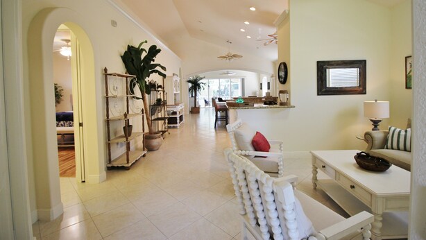 A spacious living area with a high ceiling, a dining table, a sofa, and a bookshelf. - Large Private Pool Home-Walk/Bike to Beach & Mercato Shops & Dining (Naples)