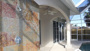 A covered outdoor area with a pool, a ceiling fan, and a view of a residential neighborhood. - Large Private Pool Home-Walk/Bike to Beach & Mercato Shops & Dining (Naples)