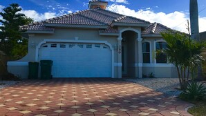 A single-story house with a tiled roof, a garage, and a paved driveway. - Large Private Pool Home-Walk/Bike to Beach & Mercato Shops & Dining (Naples)