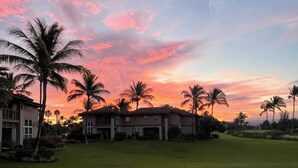 A residential area with houses, palm trees, and a sunset sky. - Last Minute Sale 50% off. Relaxing, remodeled end unit 601. Great view & 95 golf (Waikoloa)