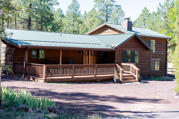 Une cabane en rondins avec un porche, une terrasse couverte et une cheminée.