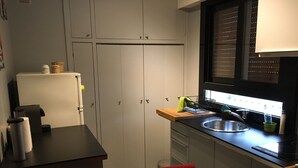 A compact kitchen with a refrigerator, sink, and a wooden table. - Modern Cozy Studio in the heart of Paris (Paris)