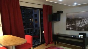 A room with a wooden table, red chairs, a black TV stand, and a cityscape painting. - Modern Cozy Studio in the heart of Paris (Paris)