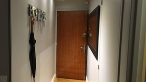 A hallway with a wooden door, a wall-mounted umbrella, and a sign with letters. - Modern Cozy Studio in the heart of Paris (Paris)