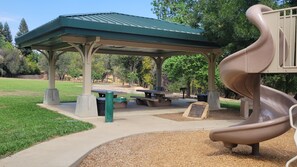 A playground with a slide, picnic tables, and a covered pavilion. - FAMILY FUN GETAWAY !! 🎱🏓RecRoom ⚽️🕹 BBQ♨️FirePit (Redding)