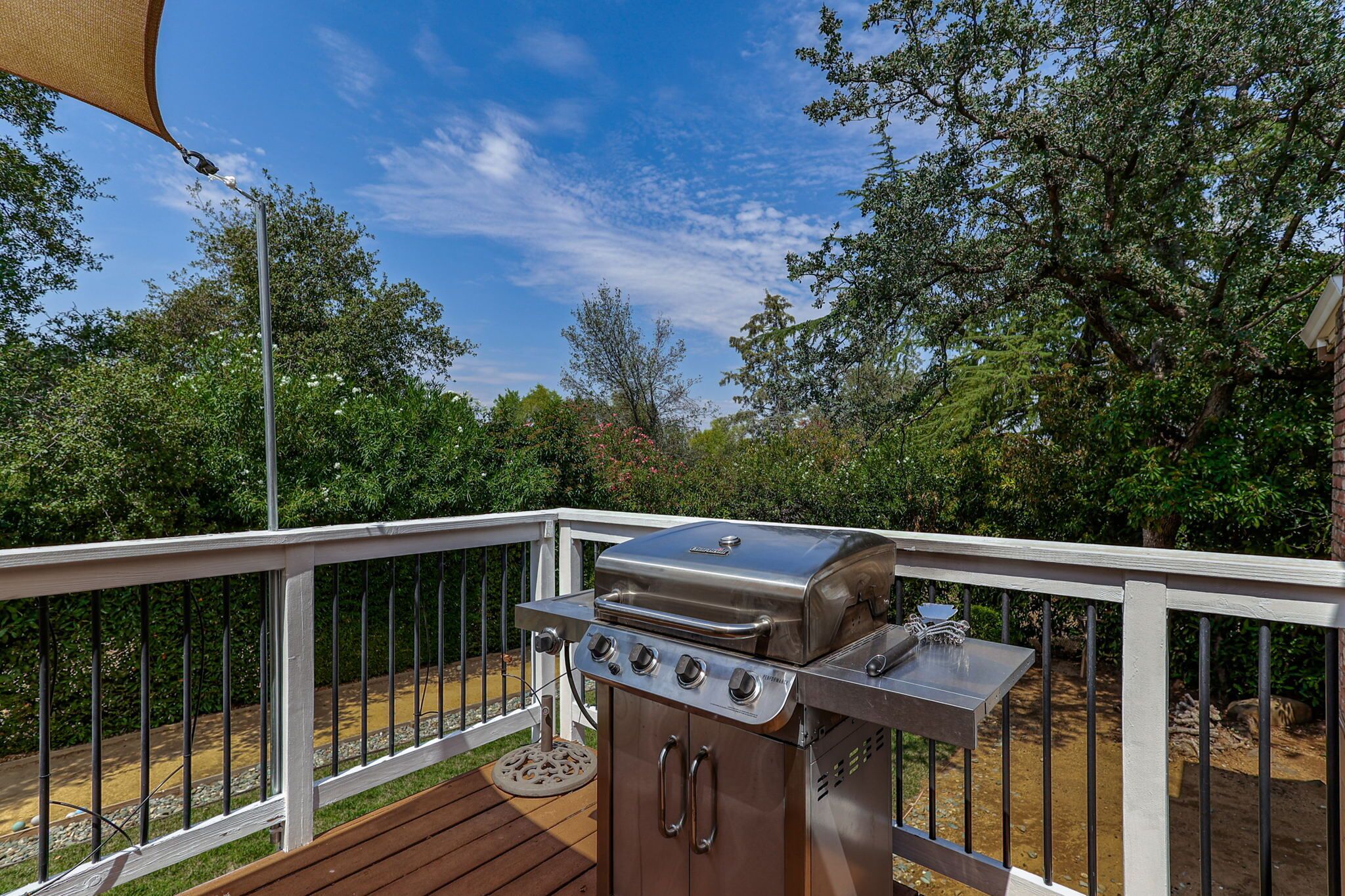 Ein Grill auf einer Terrasse mit Blick auf Bäume und einen klaren Himmel.