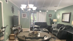 Un salon comprenant une table à manger, des chaises, un canapé et un téléviseur.