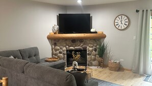 Ein modernes Wohnzimmer mit einem Ecksofa, einem Kamin, einem Flachbildfernseher und einem runden Couchtisch.