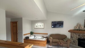 Ein modernes Wohnzimmer mit einer Holzbank, einem großen Fenster, einem Kamin aus Stein und einem flachbildfernseher an der Wand.