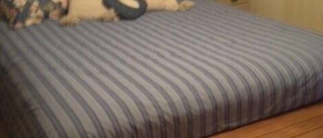 Un dormitorio con cama, almohadas, una mesita de noche y una lámpara.