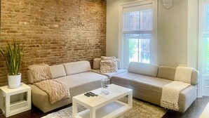 Ein Wohnzimmer mit Ziegelwand, zwei Sofas, einem Couchtisch und einer Topfpflanze.