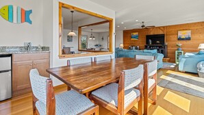 A modern kitchen with a wooden dining table and chairs, a large mirror, and a living area with a sofa and TV. - 4 Bedroom in Duck - Almost Oceanfront - Awesome views
 (Duck)