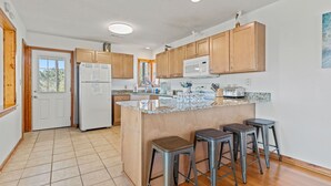 A modern kitchen with wooden cabinets, a granite countertop, and a built-in microwave. - 4 Bedroom in Duck - Almost Oceanfront - Awesome views
 (Duck)