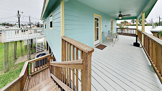 A covered porch with a wooden railing, a ceiling fan, and a view of the surrounding area. - Boat Parking, In Town, Pet Friendly, Golf Cart Access (Port Aransas)
