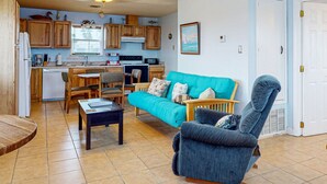 A compact living space with a kitchenette, a teal sofa, a wooden dining table, and a blue armchair. - Boat Parking, In Town, Pet Friendly, Golf Cart Access (Port Aransas)