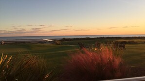A golf course with a view of the ocean at sunset.