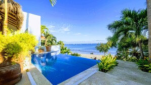 A pool with a clear view of the ocean and a beach.