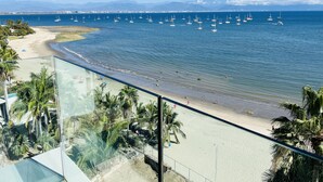 A beach with a clear view of the ocean and sailboats.