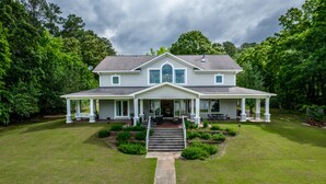 A two-story house with a front porch, a covered entryway, and a well-maintained lawn. - Lakefront/8 Acres/Views/Families/Pool Table/Fire Pit/Kayaks/SUP/Quiet/HotTub (Greensboro)