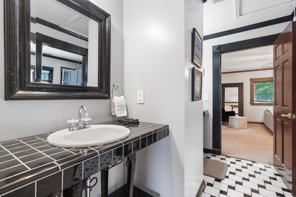 A bathroom with a white sink, black tiled countertop, and a large mirror. - Lakefront/8 Acres/Views/Families/Pool Table/Fire Pit/Kayaks/SUP/Quiet/HotTub (Greensboro)