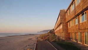 Un hotel affacciato sulla spiaggia, con facciata in legno e vialetto che conduce alla spiaggia, e vista sull'oceano.
