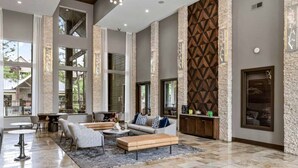 Eine geräumige Lobby mit hohen Decken, großen Fenstern und einer modernen Wand aus Stein.