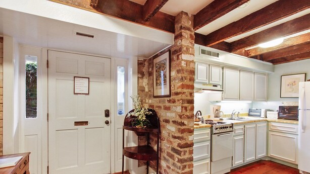 A kitchen with white cabinets, a brick column, and wooden flooring. - Garden Level of Grand Savannah Home (Savannah)