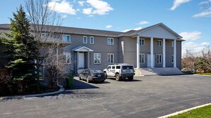 A two-story building with a driveway and parked vehicles.