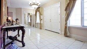 A spacious room with a chandelier, a large white door, and a window with curtains.