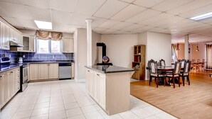 A spacious kitchen with a central island, a dining area with wooden chairs, and a view of the adjacent living room.