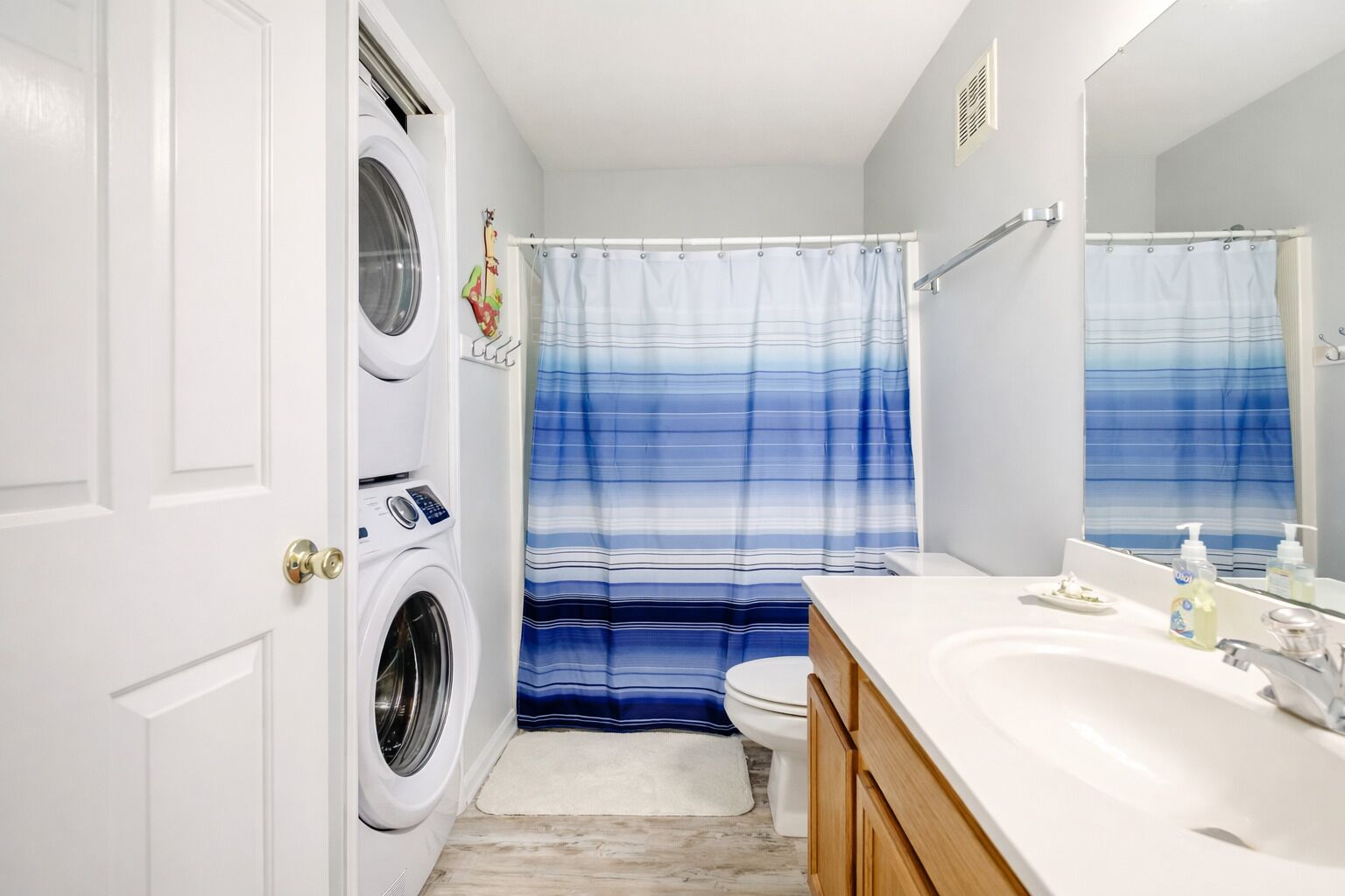 A bathroom with a washing machine, a toilet, a sink, and a shower curtain.