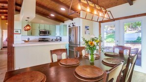Una cocina moderna con vigas de madera, un comedor con una mesa grande y vistas al exterior.