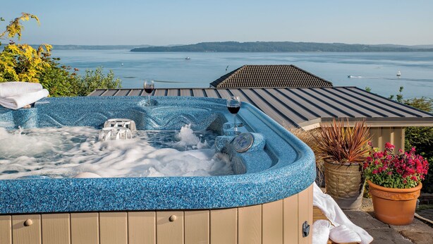 A hot tub with a view of the sea, a wooden deck, and potted plants. - Cottage with Puget Sound, Mount Rainier, & Olympic Views (Burien)