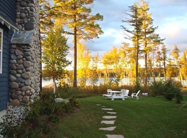 Relax in a serene setting surrounded by tall trees and a tranquil body of water.