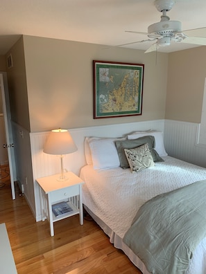 Relax in a cozy retreat with a comfortable bed, bedside table, and ceiling fan.
