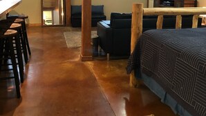 A cozy room with a wooden floor, a sofa, a TV, and a fireplace.