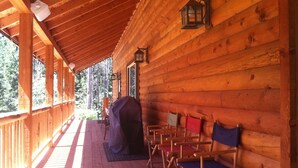 A wooden cabin with a covered porch, wooden chairs, a barbecue grill, and a lantern. - King's Cabin, just 2 miles from the Park entrance in West Glacier! (West Glacier)