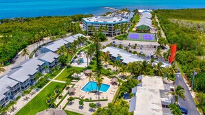 Ein Luftbild eines Resorts mit mehreren Gebäuden, einem Swimmingpool und einem Tennisplatz.