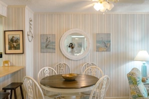 Enjoy meals in this stylish dining area with a round table, comfortable chairs, and a large mirror above.