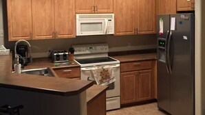 Una cucina con mobili in legno, un forno a microonde, un fornello, un frigorifero e una macchina per il caffè.
