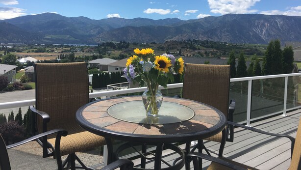 A round glass table with wicker chairs on a balcony overlooking a mountainous landscape. - Expansive views, hot tub, & kid friendly! Perfect for multiple families! (Manson)
