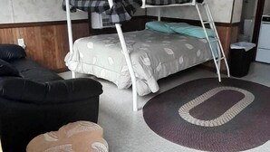 A compact room with a bunk bed, a small sofa, and a decorative rug. - Schuster's Fox River Resort on the Fox -Perch Place (Omro)