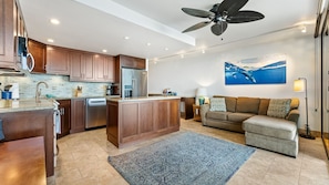 A modern kitchen with wooden cabinets, a central island, and a ceiling fan.