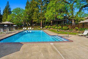 A rectangular swimming pool with a tiled edge, surrounded by lounge chairs and a paved deck. - Spacious 2BR condo with pool, fireplace,at Silverado Country Club (Napa)