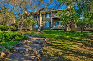A two-story building with a stone pathway leading to a grassy area.