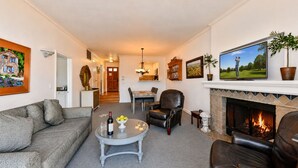 Ein Wohnzimmer mit Kamin, Ledermöbeln, einem Essbereich und einem Flur, der zur Küche führt.