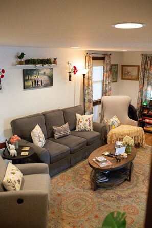 A living room with a grey sofa, a round coffee table, and a patterned rug.