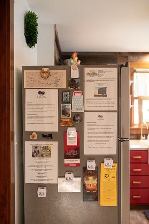A refrigerator with various papers, magnets, and notes attached to it, including a map, a menu, and a list of instructions.
