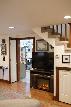 A living room with a fireplace, a television, and a staircase.